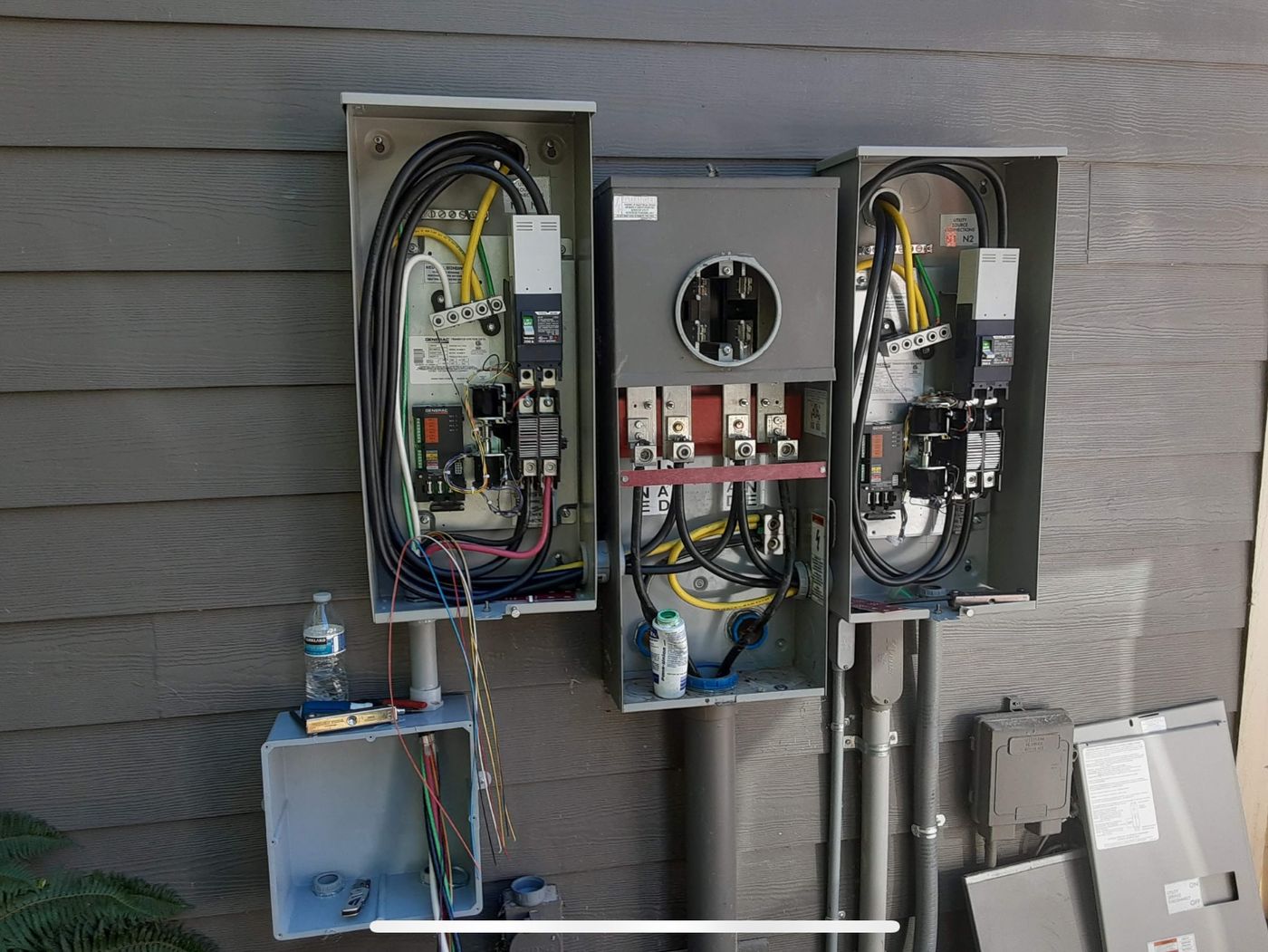 Two Generac 200 amp automatic transfer switches mounted either side of a meter main during installation