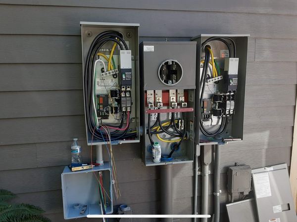 Two Generac 200 amp automatic transfer switches mounted either side of a meter main during installation